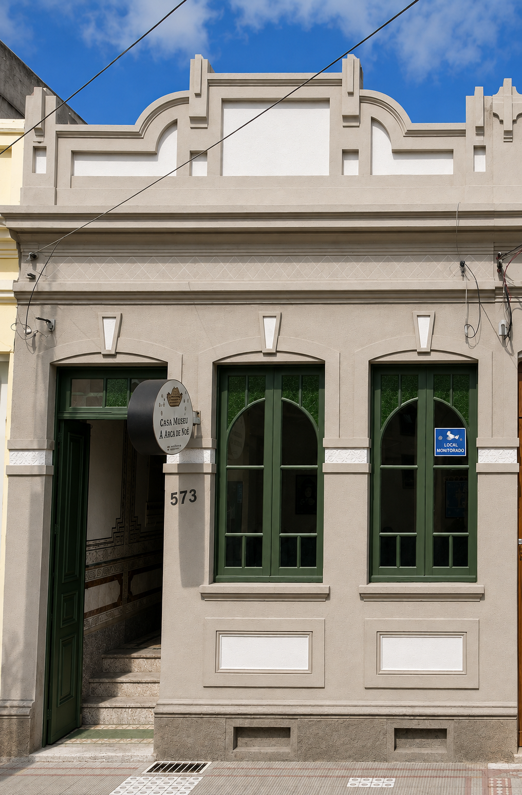 Fachada da clínica veterinária A Arca de Noé, em prédio histórico, com portas e janelas em verde e placas com a identidade da clínica.
